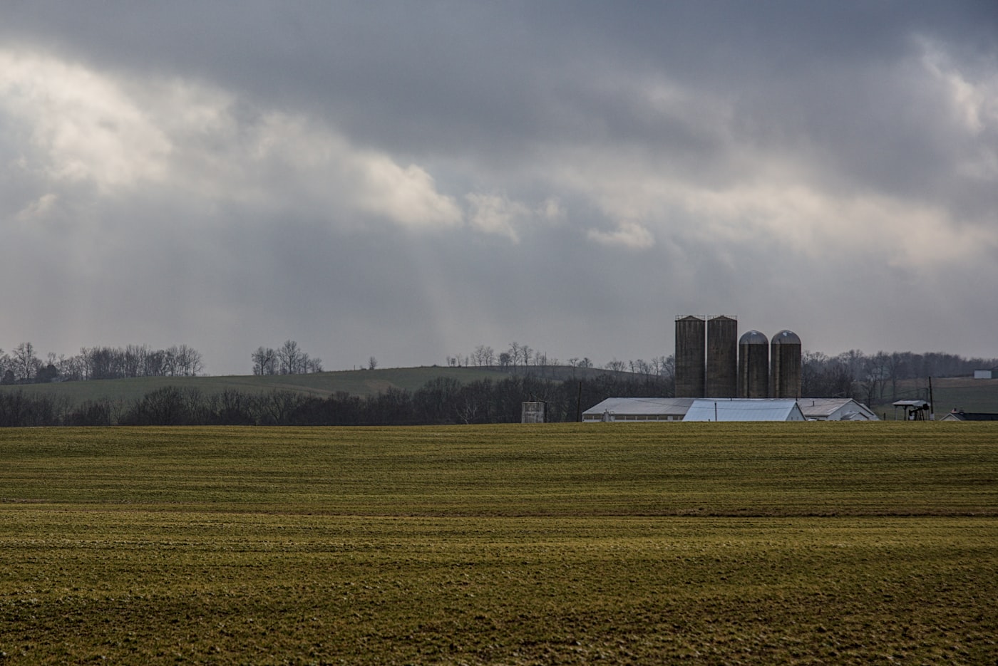 Hofstelle mit Wirtschaftsgebäude und Silos unter bewölktem Himmel